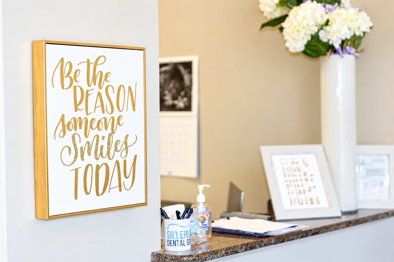 Recepción con flores y un letrero que dice “Be the reason someone smiles today”