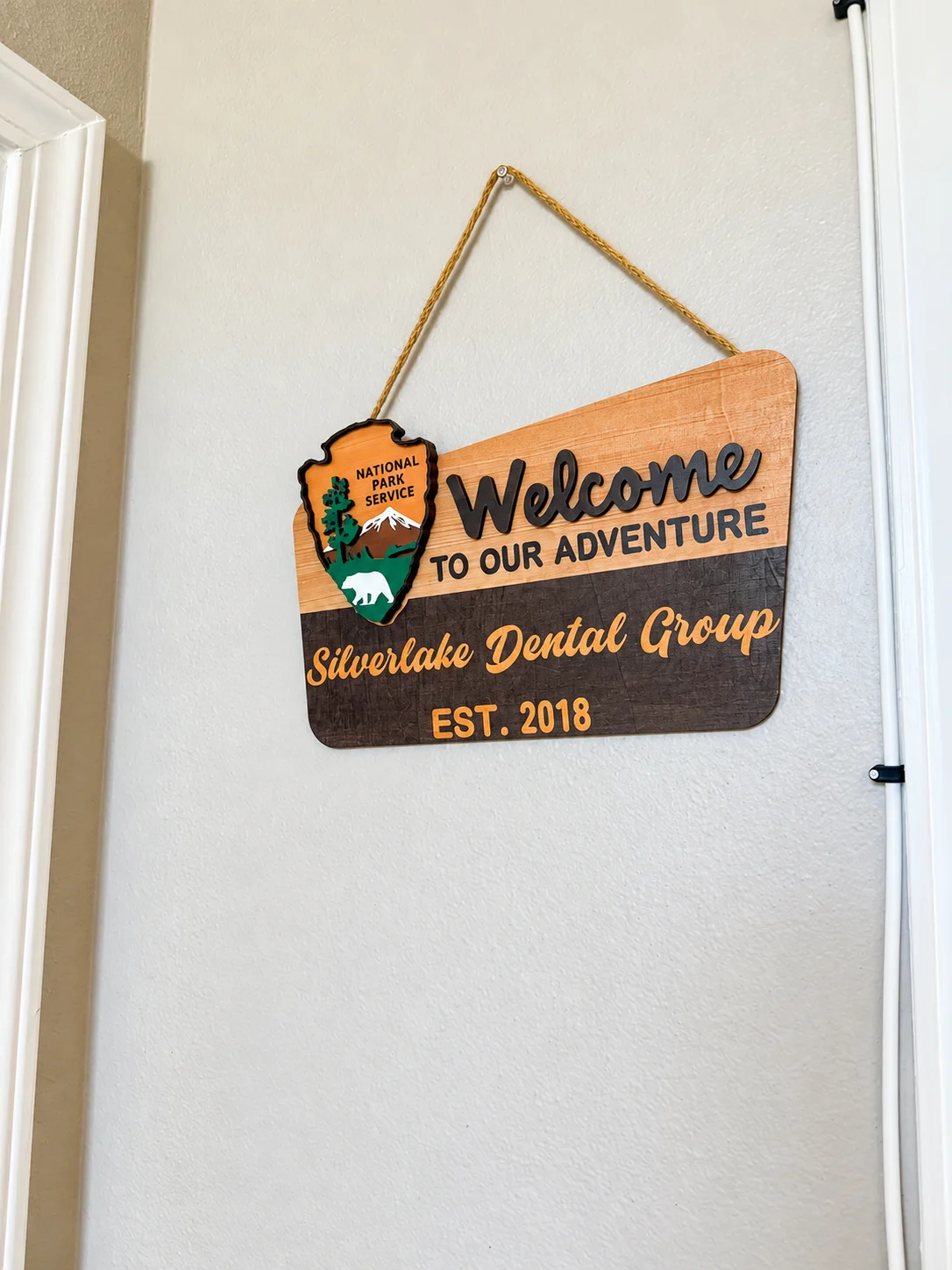 Letrero de madera con el mensaje “Welcome to our adventure” de Silverlake Dental Group, est. 2018
